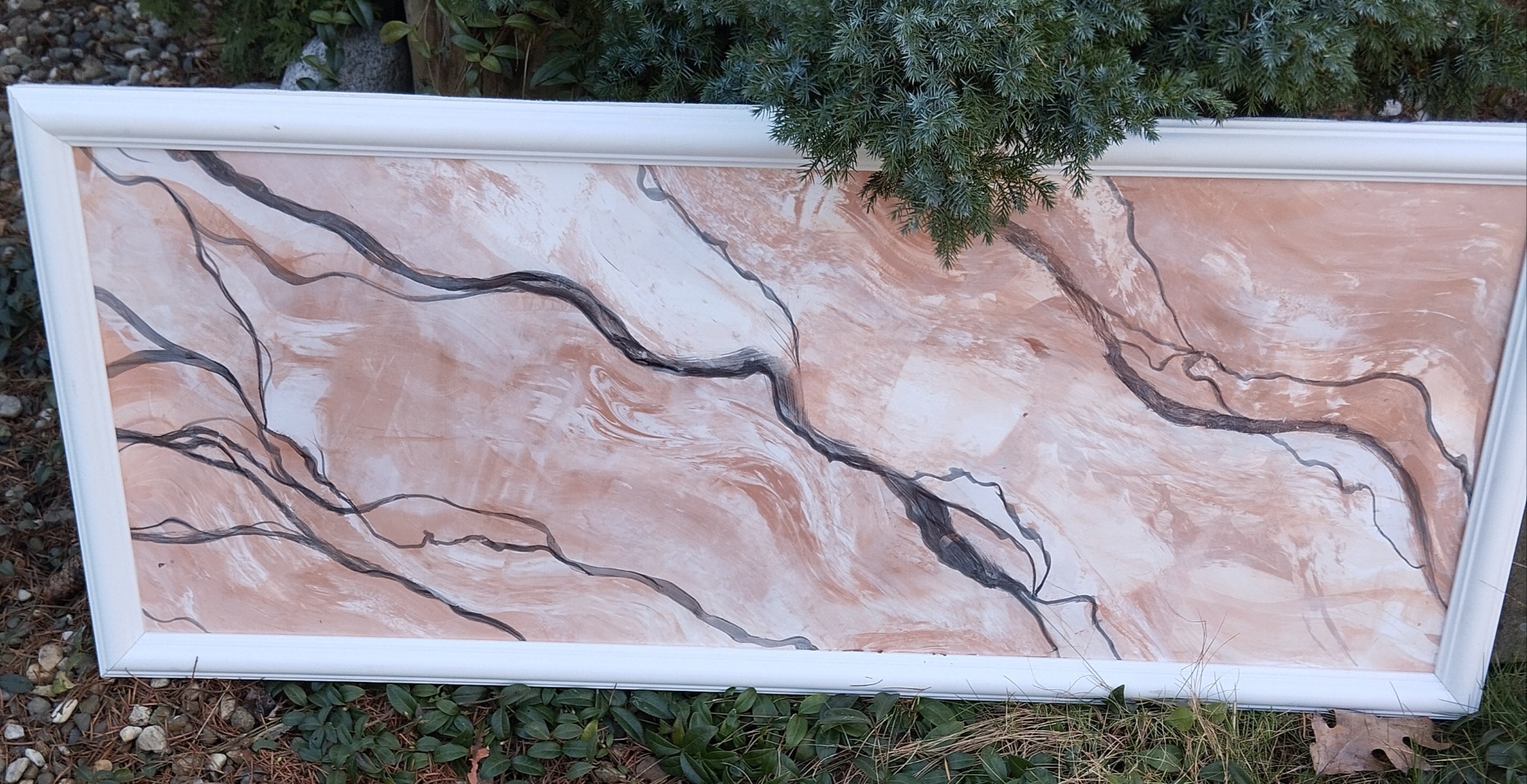 Dekoracyjna ściana z efektem marmuru w Łaziskach Górnych, obramowana białą listwą. Unikalny wzór z ciemnymi żyłkami na tle beżowo-białej powierzchni.