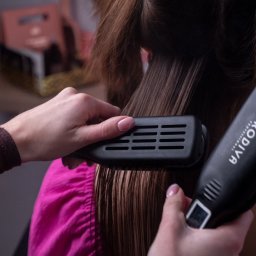 Hair New Life Angelika Wrażeń - Prostowanie wilgotnych włosów prostownicą marki Prodiva, widoczne dłonie stylistki z delikatnym manicure.