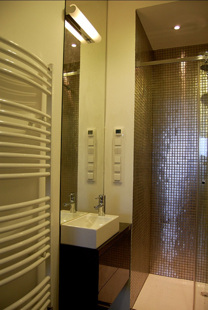 Nowoczesna łazienka z mozaiką w odcieniach złota, prostokątną umywalką nablatową, grzejnikiem drabinkowym i lustrem z oświetleniem.