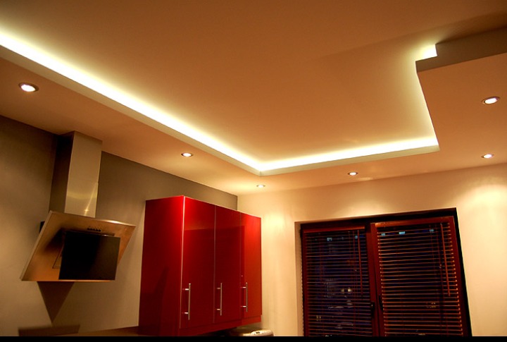 Wykończona kuchnia z podwieszanym sufitem z oświetleniem LED, czerwone szafki i nowoczesny okap.