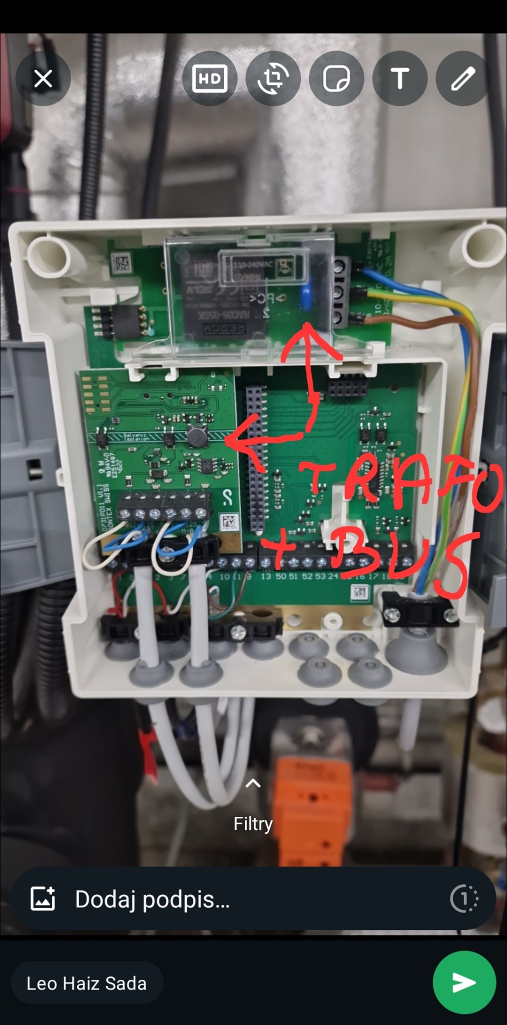 Otwarta obudowa sterownika z widocznymi płytkami drukowanymi, transformatorem i złączami kablowymi, oznaczona czerwonymi napisami 'TRAFO + BUS'.