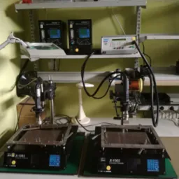 Stanowisko do naprawy elektroniki z dwoma podgrzewaczami konwekcyjnymi X-1003, systemami FOCUS 'X' SMT i oświetleniem roboczym na półkach.