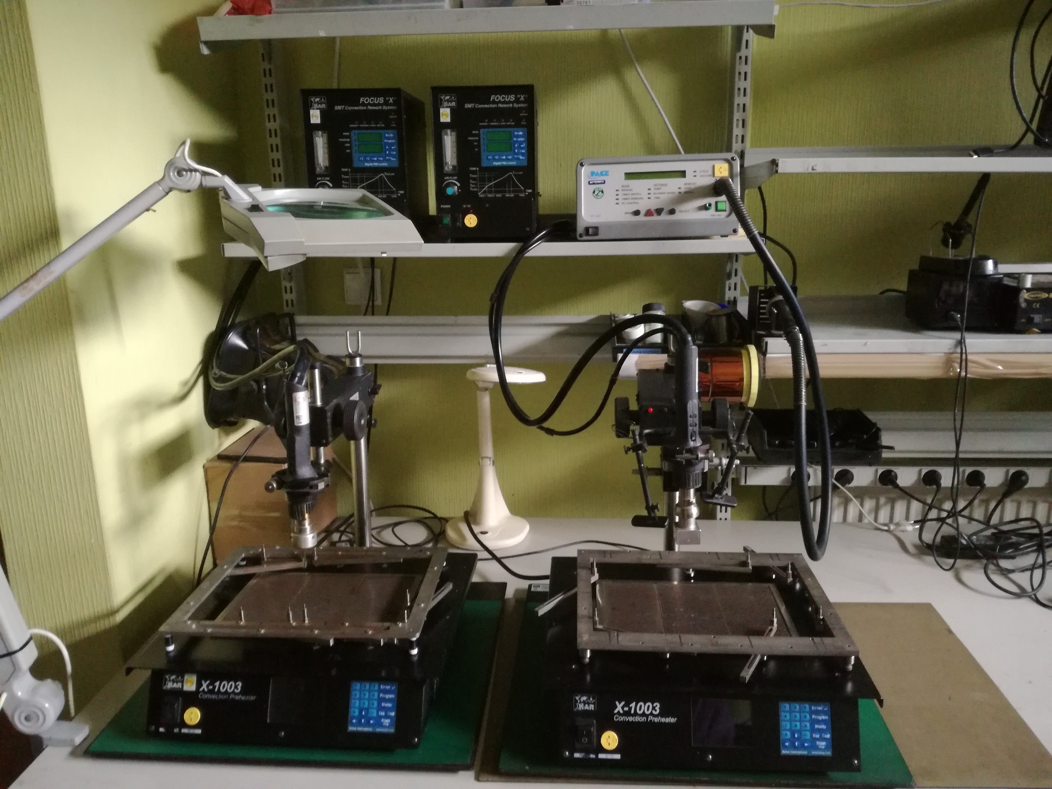 Stanowisko do naprawy elektroniki z dwoma podgrzewaczami konwekcyjnymi X-1003, systemami FOCUS 'X' SMT i oświetleniem roboczym na półkach.