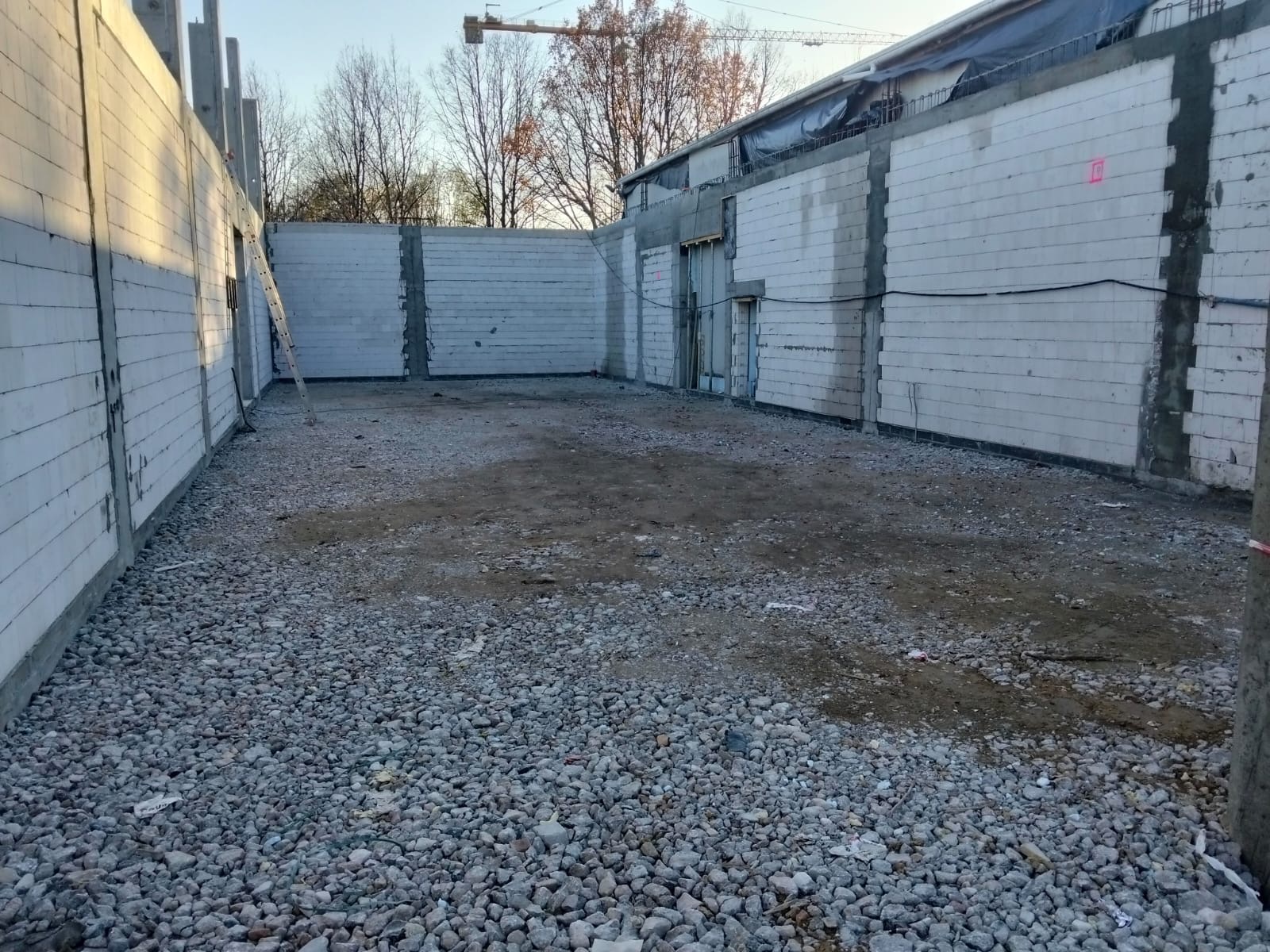 Wznoszenie ścian z bloczków betonu komórkowego na budowie w Warszawie. Widoczny fragment konstrukcji i drabina oparta o ścianę. Surowy stan.