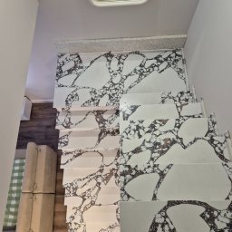 JFM Stone - Białe schody z unikalnym wzorem marmuru, widok z góry, z odbiciem w lustrze. Nowoczesne wykończenie wnętrza, jasne ściany, minimalistyczny design.