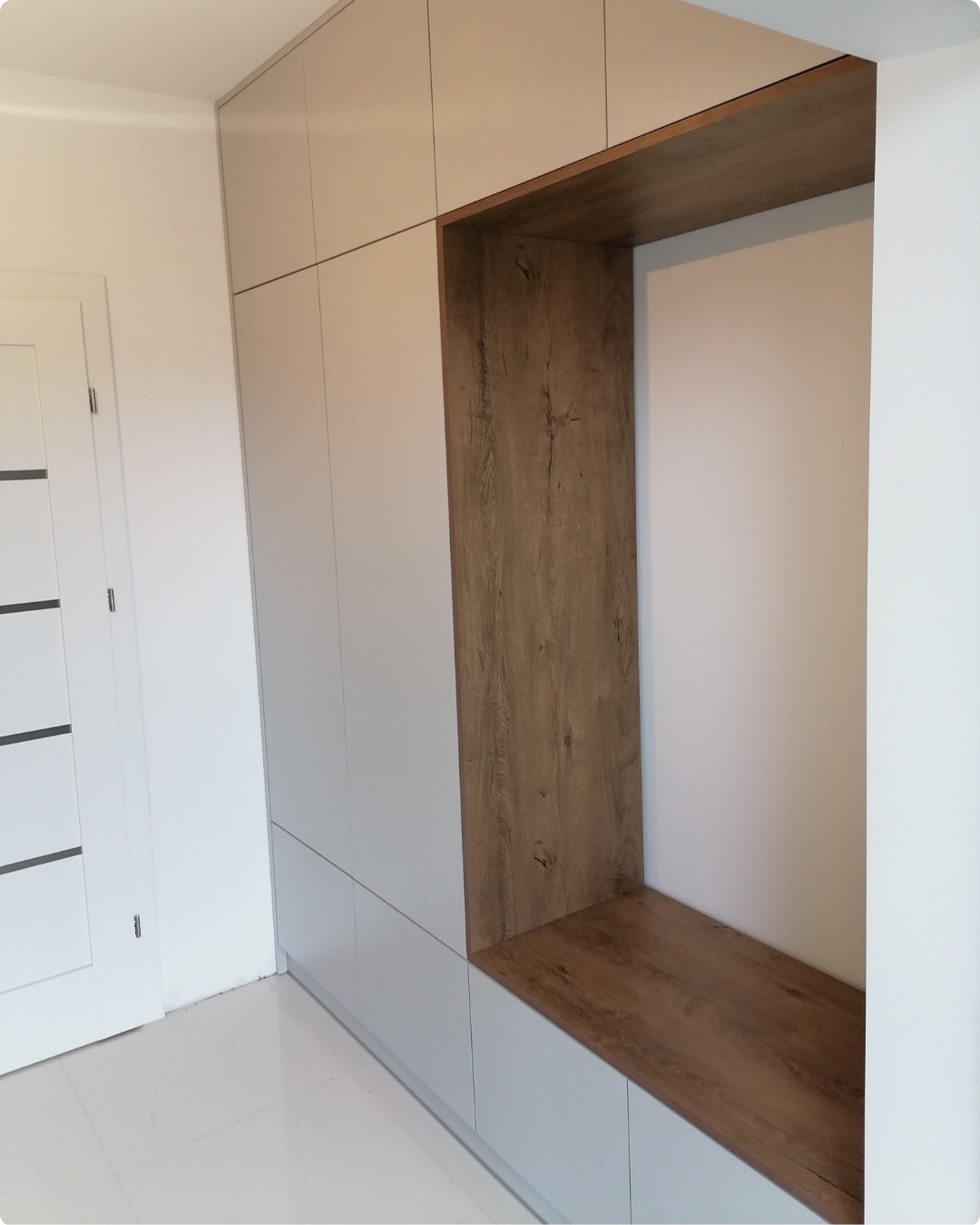 Biała szafa wnękowa z drewnianą wnęką i siedziskiem w stylu minimalistycznym.