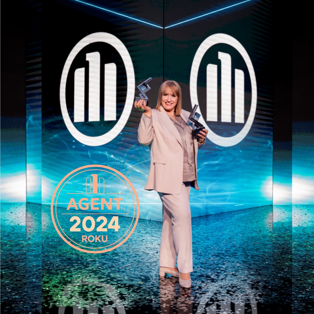 Kobieta w beżowym garniturze, trzymająca dwie statuetki na tle sceny z logo firmy ubezpieczeniowej i napisem 'Agent 2024 Roku'.