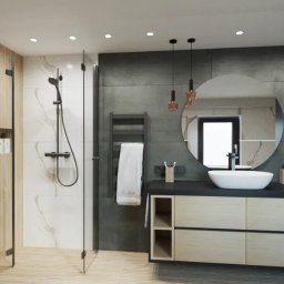 Igor tam - Nowoczesna łazienka z kabiną prysznicową typu walk-in, okrągłym lustrem, umywalką nablatową i drewnopodobnymi płytkami na podłodze, oświetlona trzema wiszącymi lampami z miedzianymi akcentami.