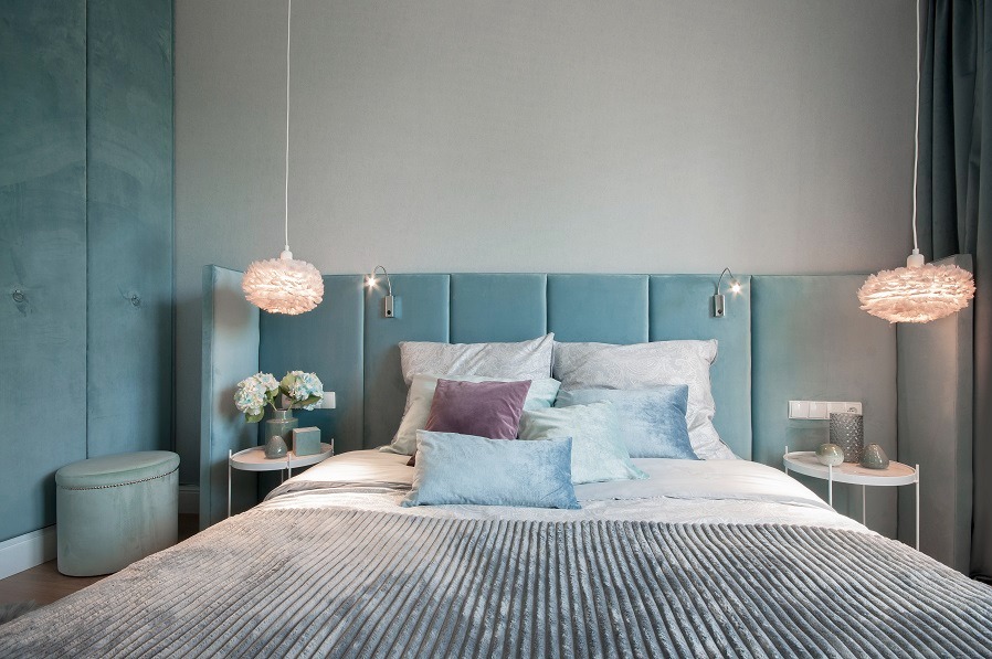 Turkusowa sypialnia w Warszawie z miękkim, pikowanym zagłówkiem, puszystymi lampami wiszącymi i dekoracyjnymi poduszkami w pastelowych odcieniach.