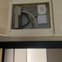 KDF Construction Group Karalina Fabiianska - Otwarta skrzynka z instalacją elektryczną: listwa zaciskowa, gniazdo podwójne i perforowana płyta montażowa, widoczne przewody elektryczne.