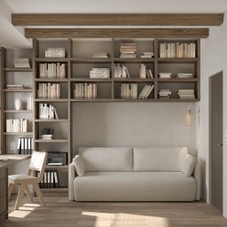 AWÓ. STUDIO PROJEKTOWE ANNA WÓJCIK - Pokój dzienny z drewnianym regałem na książki nad szarą sofą, biurkiem z krzesłem i lampą ścienną, w ciepłym oświetleniu.
