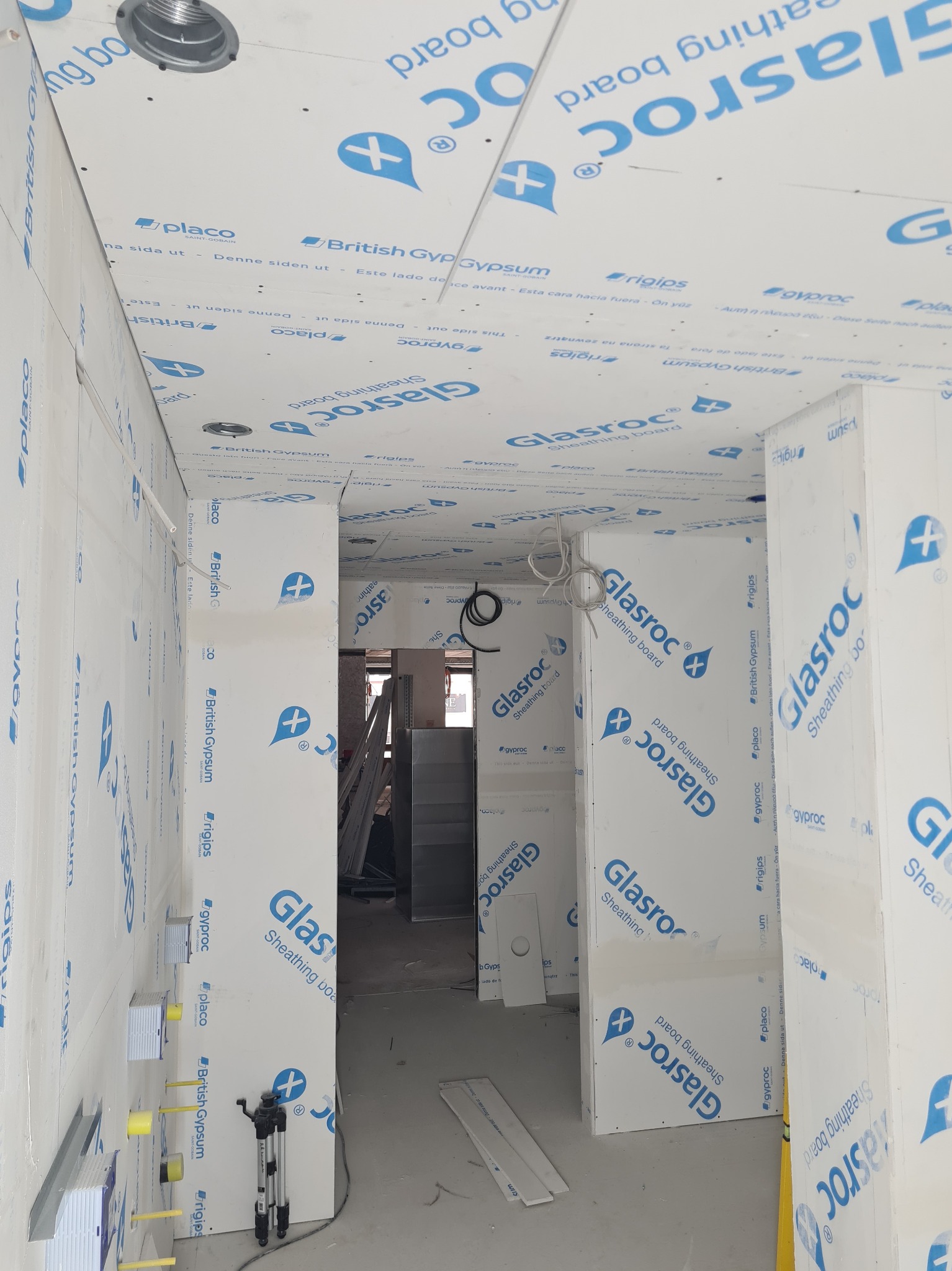 Wnętrze w trakcie wykańczania, ściany i sufit pokryte płytami Glasroc z widocznymi łączeniami i elementami instalacji elektrycznej.