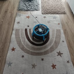 Firma sprzątająca PERFEKT Justyna Malinowska - Dwa dywany suszone za pomocą wentylatorów podłogowych po zabiegu czyszczenia. Jeden dywan z motywem gwiazd i tęczy, drugi shaggy.