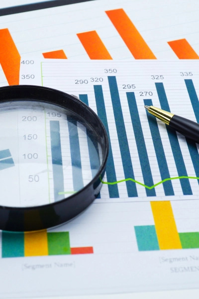 Lupa i długopis na wydrukowanym wykresie słupkowym i liniowym z danymi liczbowymi, analiza danych finansowych.