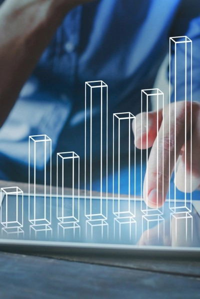 Palec wskazujący na tablet z nałożonym graficznym wykresem słupkowym, symbolizującym wzrost, na tle niebieskiej koszuli.