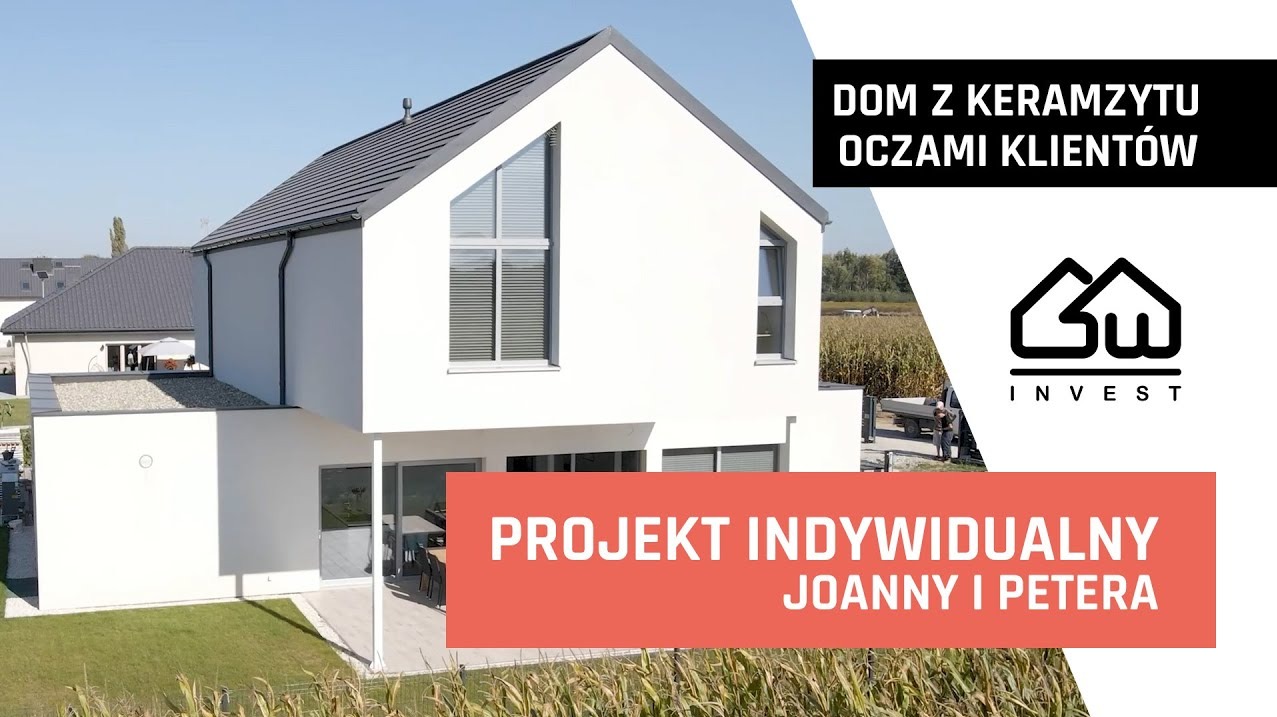 Nowoczesny dom z keramzytu z szarym dachem widziany z zewnątrz, z ogrodem i polem kukurydzy w tle. Projekt indywidualny Joanny i Petera.