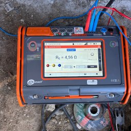 Energy 4 you Krzysztof Słomka - Miernik Sonel MPI-540-PV z wyświetloną wartością rezystancji uziemienia 4,56 Ω, podłączony przewodami pomiarowymi. Widoczne narzędzia i podłoże.