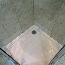 Hydro-mił Usługi Hydrauliczne - Narożna kabina prysznicowa z brodzikiem i zielonymi płytkami imitującymi marmur. Widok z góry na zamontowaną kabinę.