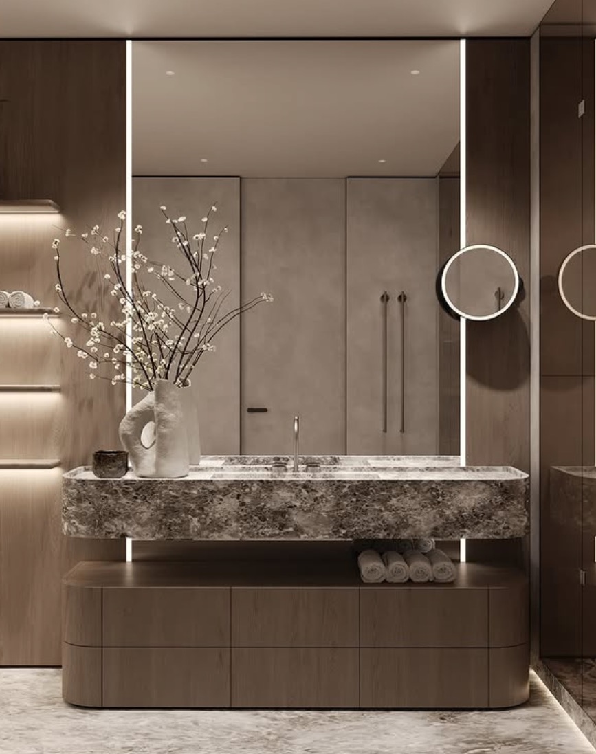 Nowoczesna łazienka w odcieniach beżu i szarości. Marmurowa umywalka, minimalistyczna armatura, oświetlenie LED i dekoracyjne okrągłe lustra tworzą elegancki klimat.