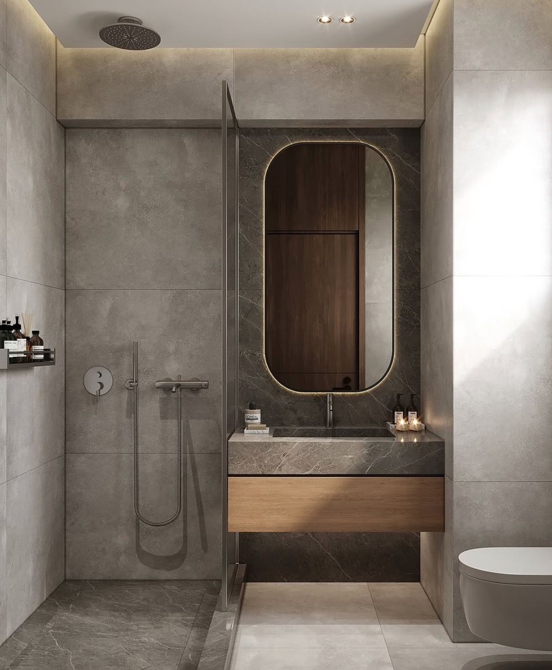 Nowoczesna łazienka z szarymi płytkami imitującymi kamień, podświetlanym lustrem w zaokrąglonej ramie i drewnianą szafką pod umywalką. Minimalistyczny design z kabiną prysznicową.
