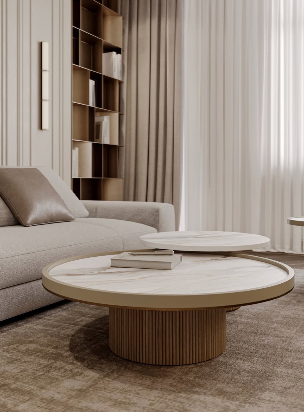 Jasne wnętrze salonu z okrągłym stolikiem kawowym z marmurowym blatem, beżowa sofa z poduszką i regał na książki w tle, tworzące spójną aranżację.