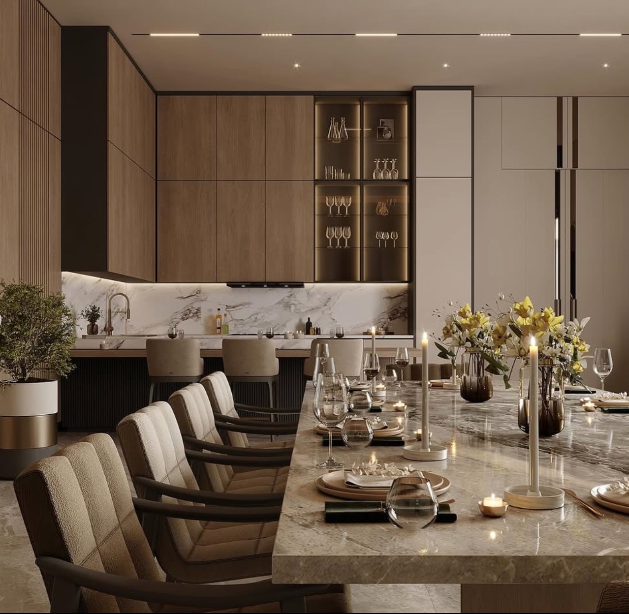 Elegancka jadalnia z marmurowym stołem, krzesłami w beżowej tapicerce, oświetleniem punktowym i zabudową kuchenną w odcieniach brązu i beżu. Dekoracyjne świece i kwiaty.