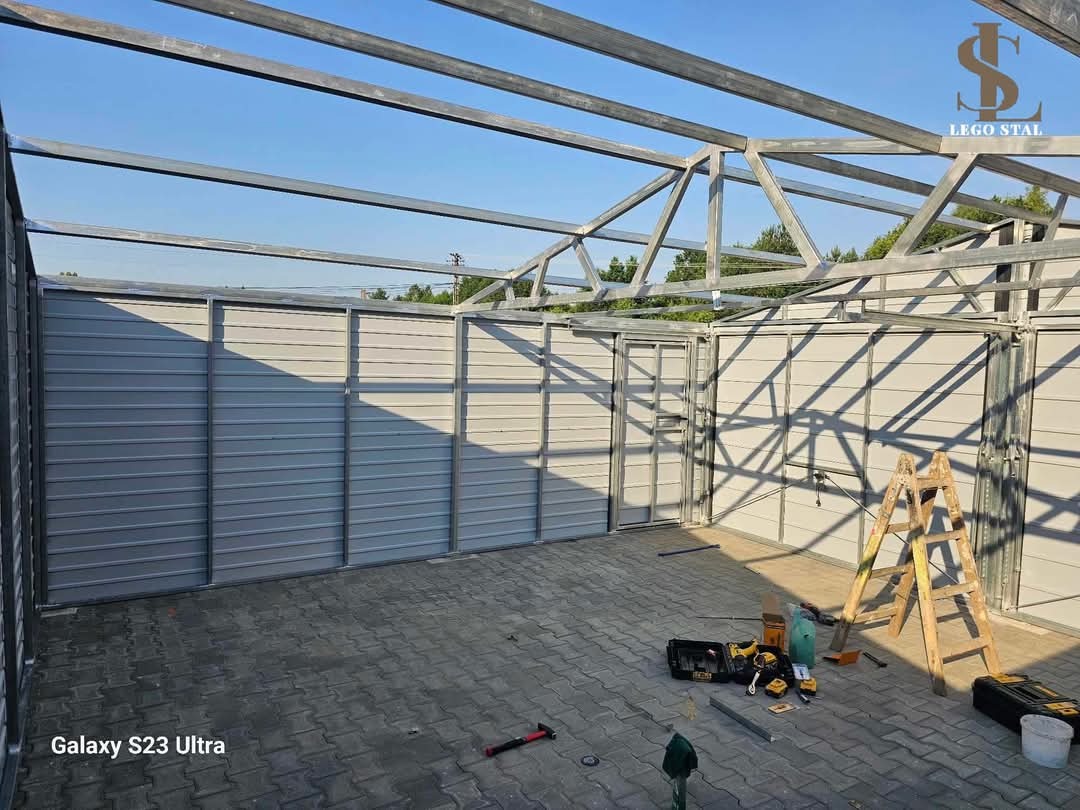 Montaż konstrukcji stalowej z blachy falistej, widoczne narzędzia, drabina i logo firmy Lego Stal w prawym górnym rogu.