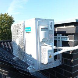 ETP Solution - Zewnętrzna jednostka klimatyzacji Hisense zamontowana na wsporniku na dachu z czarnej dachówki, z widocznym przewodem w izolacji prowadzącym do ściany z cegły.