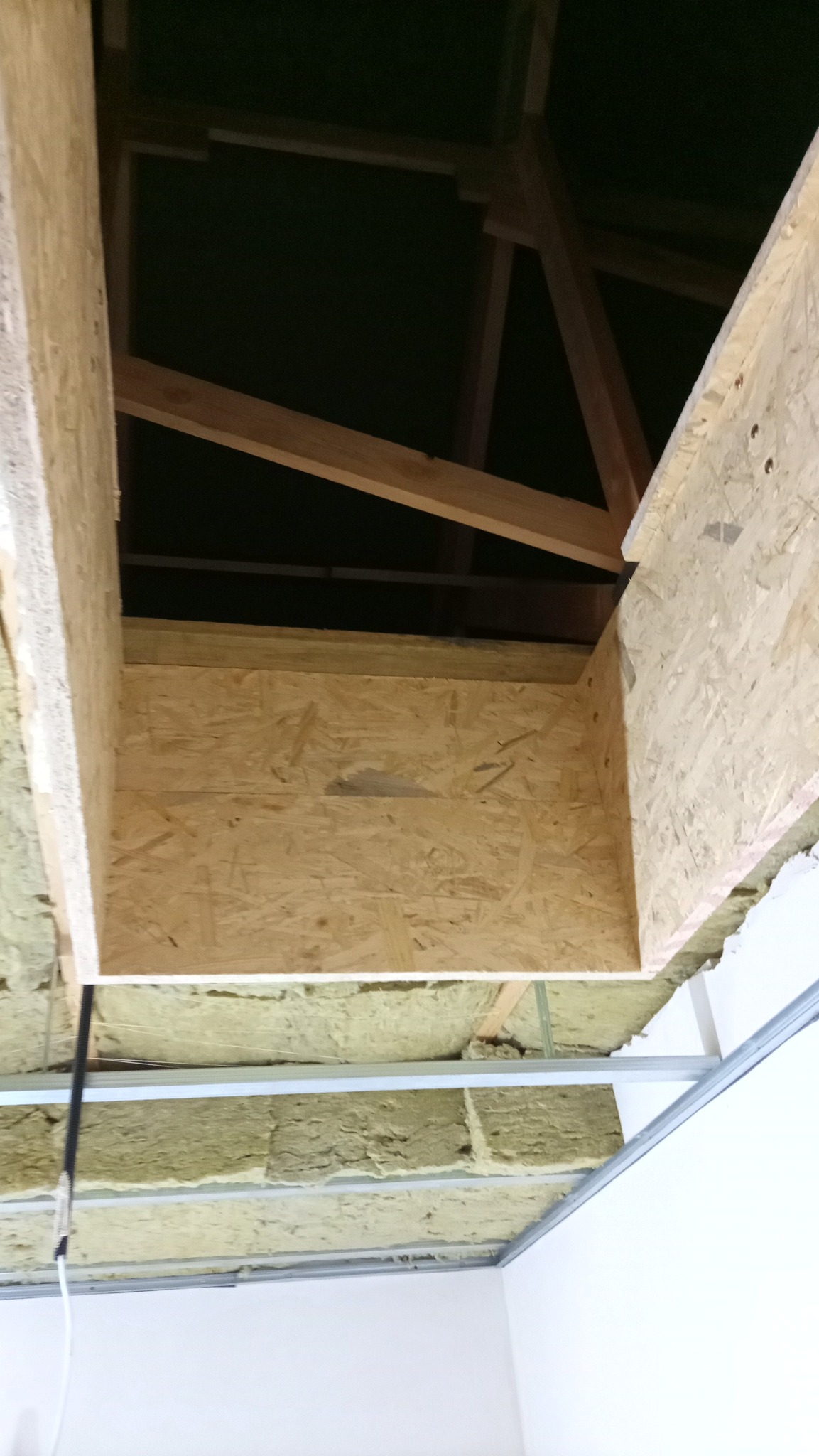 Sufit podwieszany z izolacją z wełny mineralnej i konstrukcją z płyty OSB, widok z dołu, surowy stan przed wykończeniem.