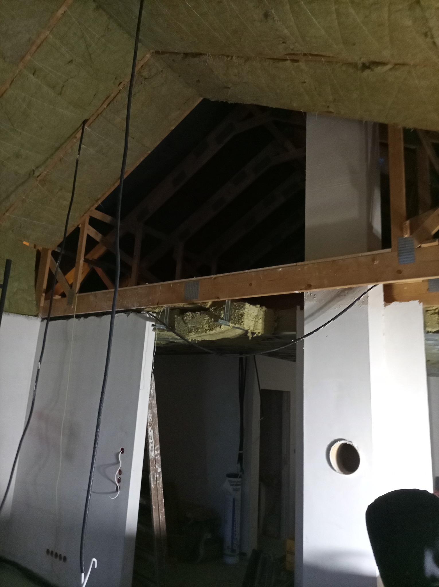 Poddasze w trakcie adaptacji: ocieplenie wełną mineralną, konstrukcja drewniana, ściany z płyt gipsowo-kartonowych z widocznymi przewodami elektrycznymi. Prace wykończeniowe.