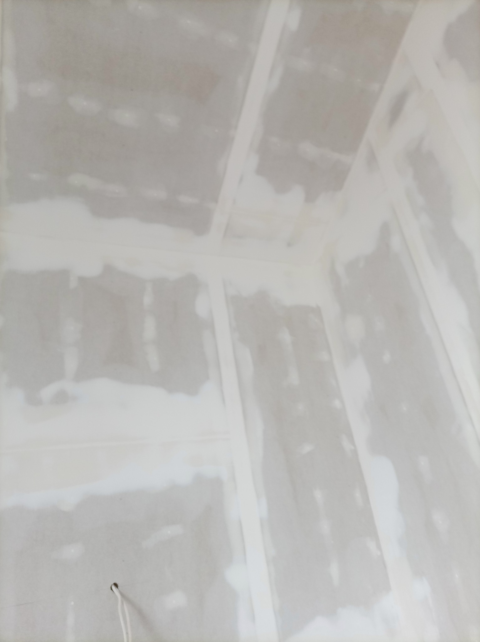 Wnętrze w trakcie prac wykończeniowych: widoczne płyty karton-gips na ścianach i suficie, zaszpachlowane łączenia. Ujęcie z dołu, podkreślające geometrię pomieszczenia.