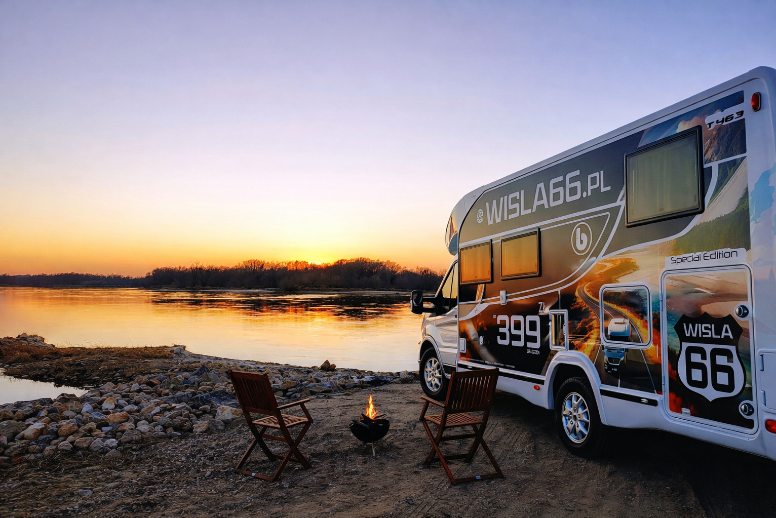 Kamper Wisla66.pl na tle rzeki i zachodzącego słońca. Dwa krzesła i małe ognisko tworzą klimat biwakowy. Widoczny branding pojazdu.