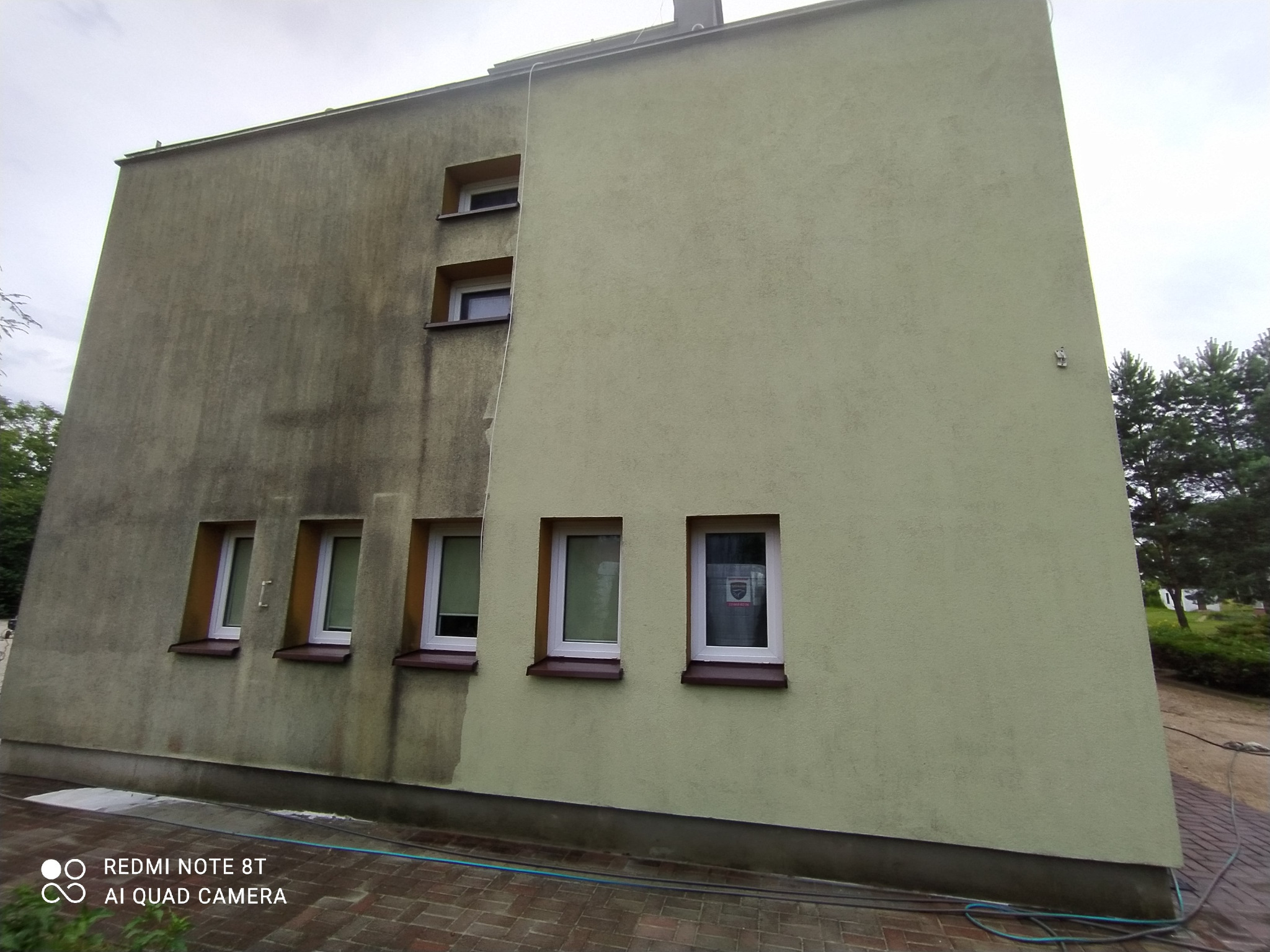 Porównanie umytej i brudnej elewacji budynku z oknami, widoczne różnice w kolorze i czystości, efekt przed i po myciu.