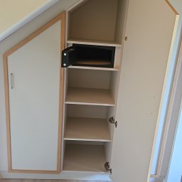 Patryk Marek Góral dom - Wnękowa szafa z otwartymi drzwiami, z drewnianą ramą i sejfem w środku, na jasnej podłodze.