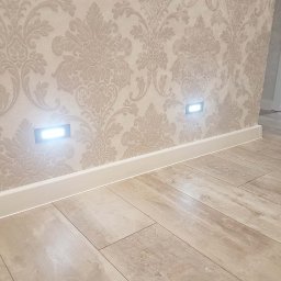 Dzmitry Sharakhouski - Wnętrze z podświetlanymi listwami przypodłogowymi i tapetą w ornamenty, podłoga imitująca drewno.