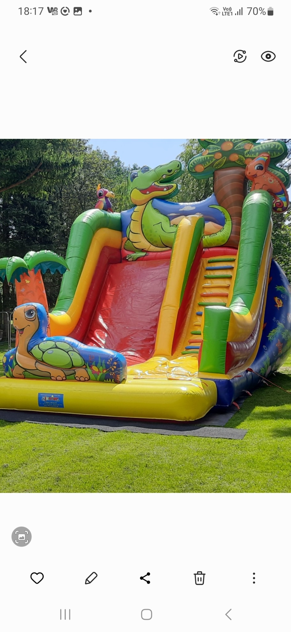 Kolorowa dmuchana zjeżdżalnia z motywami zwierzęcymi, w tym krokodylem i żółwiem, ustawiona na trawniku.