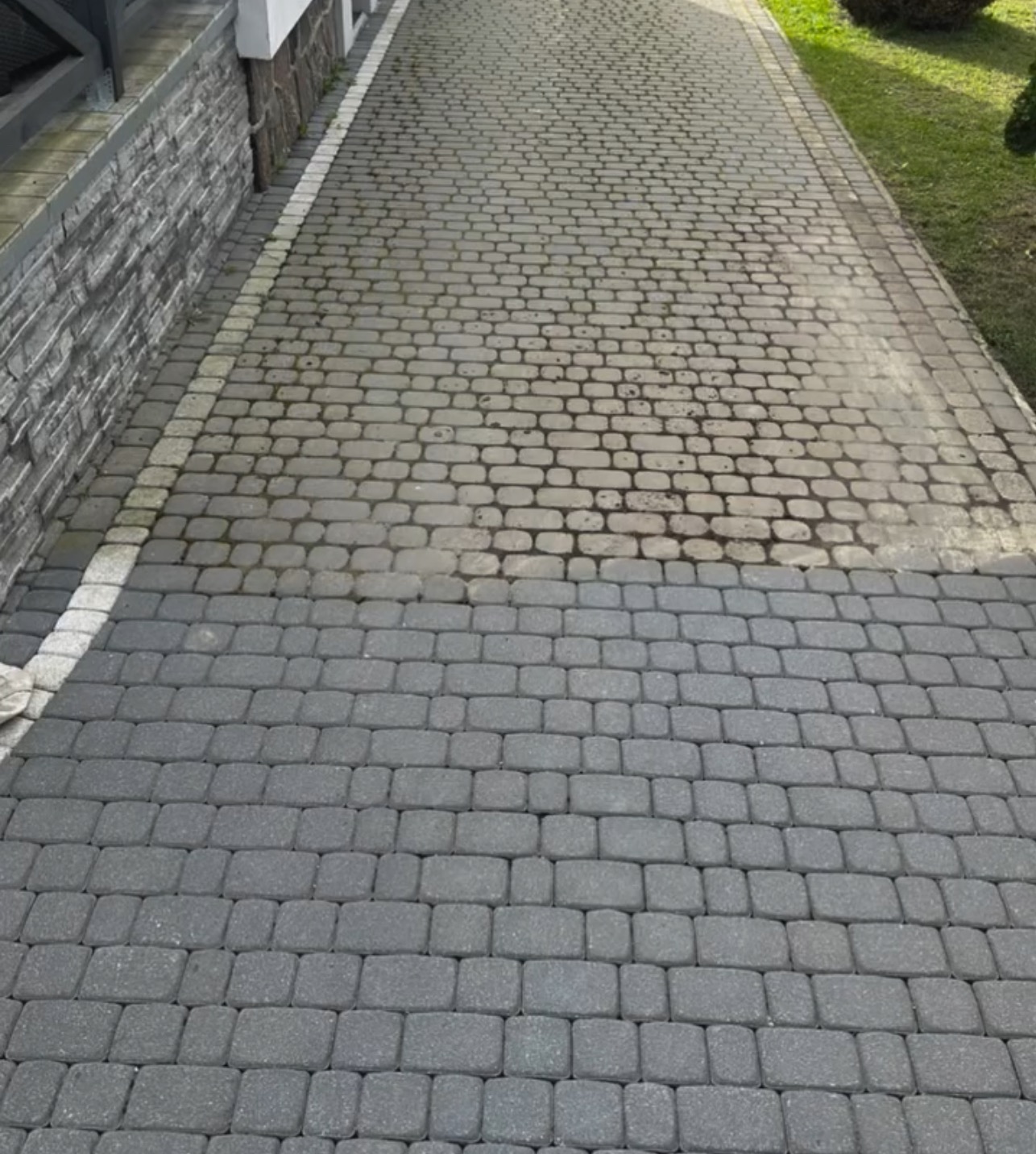 Częściowo wyczyszczona kostka brukowa w odcieniach szarości, widoczna różnica w kolorze między czystą a brudną powierzchnią.