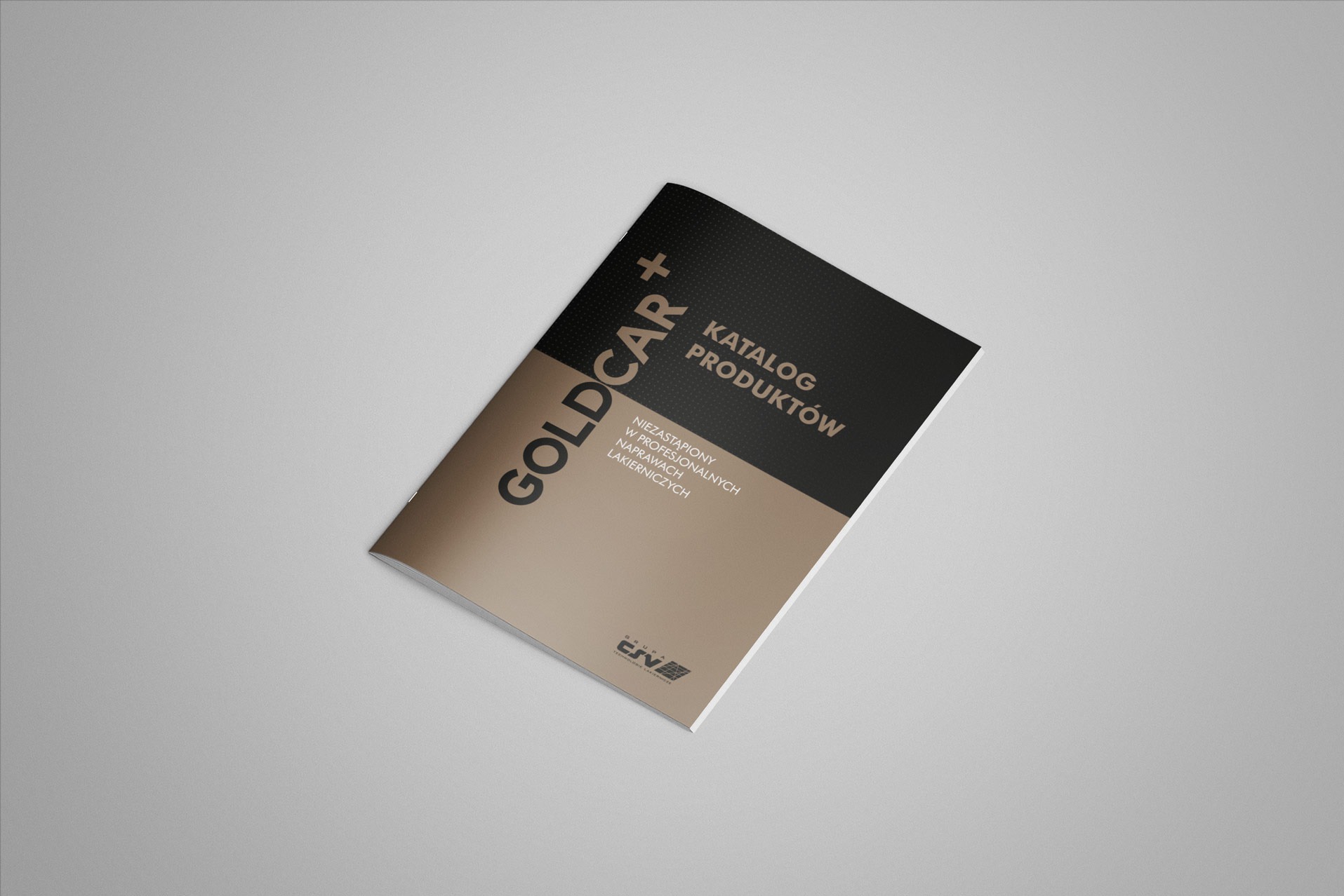 Katalog produktów Goldcar+ na beżowo-czarnym tle, leżący ukośnie na jasnoszarym tle.