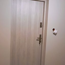 FIRMA BUDOWLANO-HANDLOWO-USŁUGOWA BAZ-BUD Mariusz BAZAN - Drzwi wejściowe w trakcie remontu, widoczna skrzynka elektryczna bez osłony i wystające przewody.