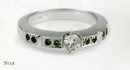 Pierścionek zaręczynowy z białego złota z diamentem i zielonymi kamieniami szlachetnymi, prezentowany przez jubilera z Warszawy.