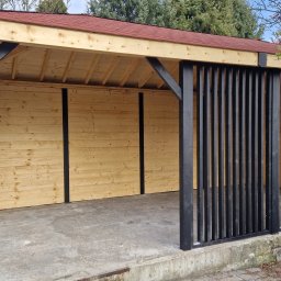 ALBERO Mateusz Kosiń - Drewniana wiata z czerwonym dachem, czarnymi słupami i ażurowymi panelami. Konstrukcja z jasnego drewna, betonowa podstawa. Widok na ogród i drzewa.