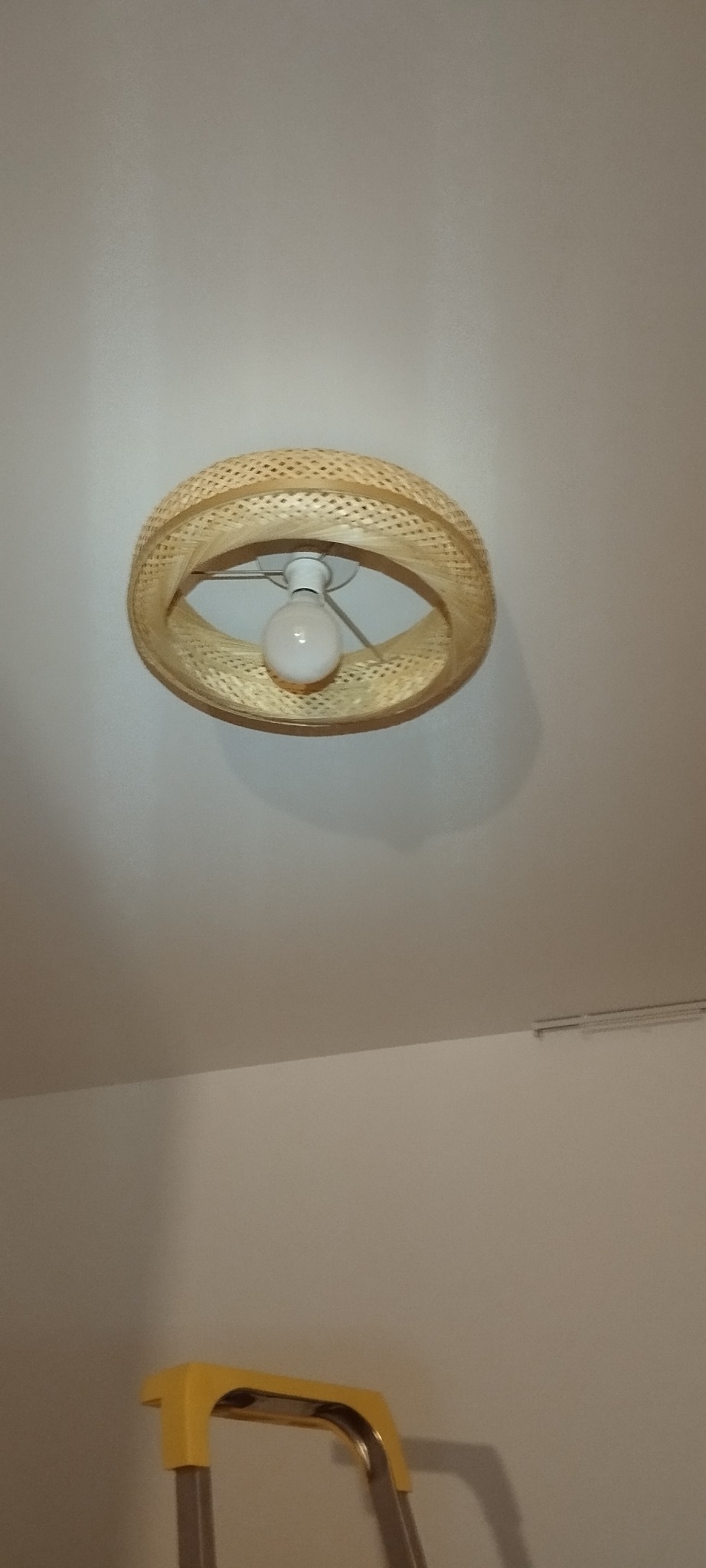 Zamontowana lampa sufitowa z abażurem z naturalnego rattanu, widoczna z dołu, pod spodem drabina.