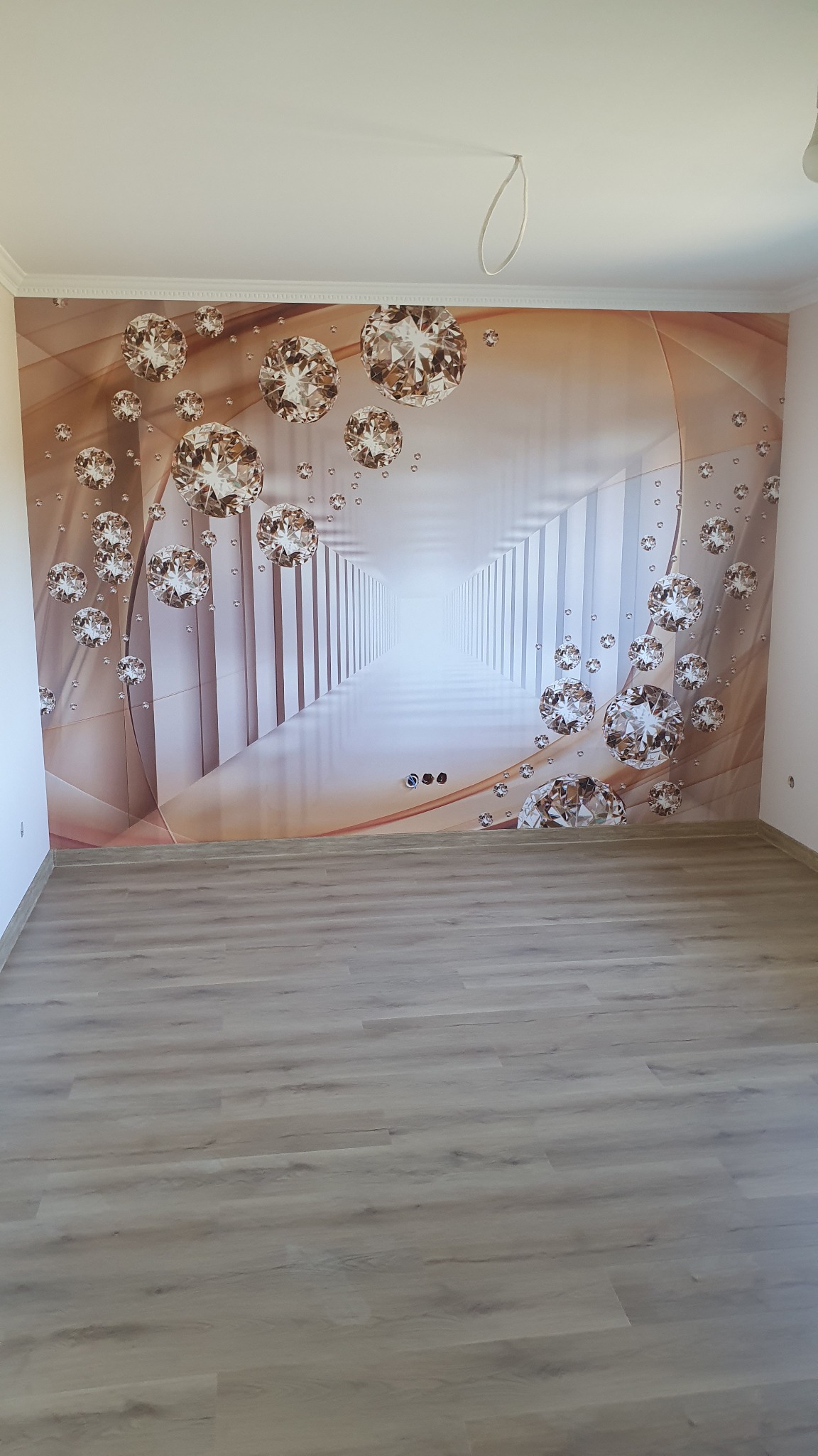 Pokój po położeniu paneli podłogowych, z fototapetą przedstawiającą tunel z motywem diamentów na ścianie.