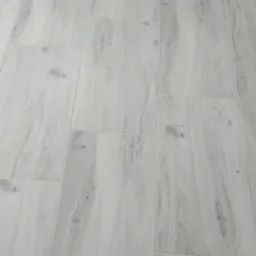 Jasnoszare panele podłogowe z widocznym grzejnikiem żeliwnym przy ścianie.