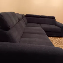 Ciemnoszary narożnik z regulowanymi zagłówkami, widok z niskiej perspektywy, ukazujący fakturę tkaniny i wzór dywanu w tle.