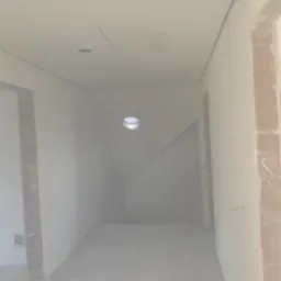 Wnętrze w trakcie prac wykończeniowych: surowe ściany z widocznymi fragmentami cegieł, świeżo położony gips na ścianach i suficie, widoczne otwory pod oświetlenie.