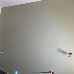 Oleksandr Kirichenko - Świeżo pomalowana ściana w odcieniach zieleni z widocznymi gniazdkami elektrycznymi. Fragment białej ściany po lewej stronie. Prace wykończeniowe w trakcie.