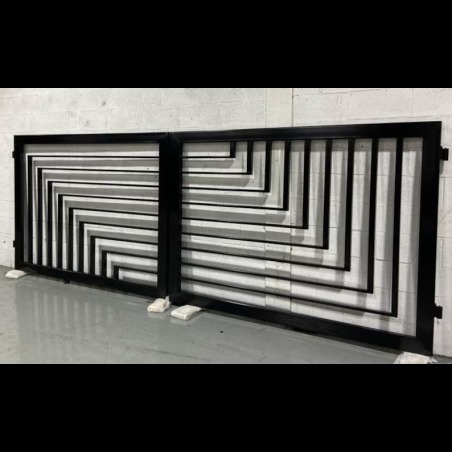 Nowoczesna, dwuskrzydłowa brama wjazdowa z czarnych, metalowych profili o geometrycznym wzorze, oparta o białe podkładki, na tle szarej ściany i podłogi.