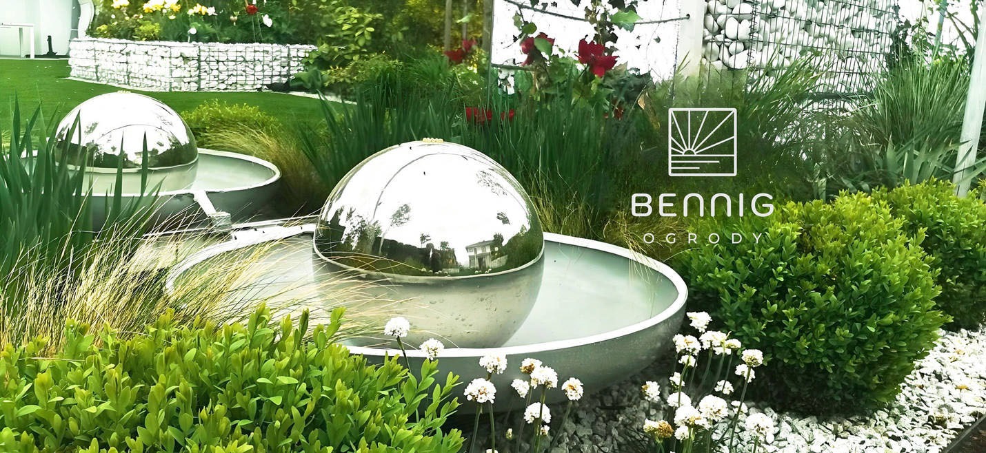 Nowoczesny ogród z metalowymi kulami wodnymi, bujną roślinnością i białymi kamieniami. W tle siatka gabionowa i logo firmy ogrodniczej.