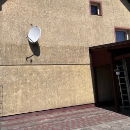 Michał Obarzanek Clean Brothers - Fragment elewacji domu z widocznym śladem po myciu pod anteną satelitarną. Na ścianie widoczna drabina i kostka brukowa.